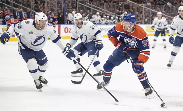 Tampa Bay Lightning's Darren Raddysh (43) and Brayden Point (21) try to defend against Edmonton Oilers' Connor McDavid (97) during the second period of an NHL hockey game, Tuesday, Dec. 10, 2024 in Edmonton, Alberta. (Jason Franson/The Canadian Press via AP)