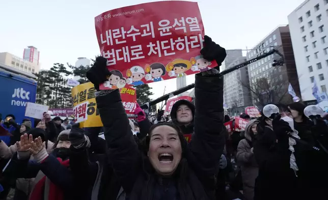 Participants celebrate after hearing the news that South Korea's parliament voted to impeach President Yoon Suk Yeol outside the National Assembly in Seoul, South Korea, Saturday, Dec. 14, 2024. The signs read "Punish the rebellion leader Yoon Suk Yeol." (AP Photo/Ahn Young-joon)