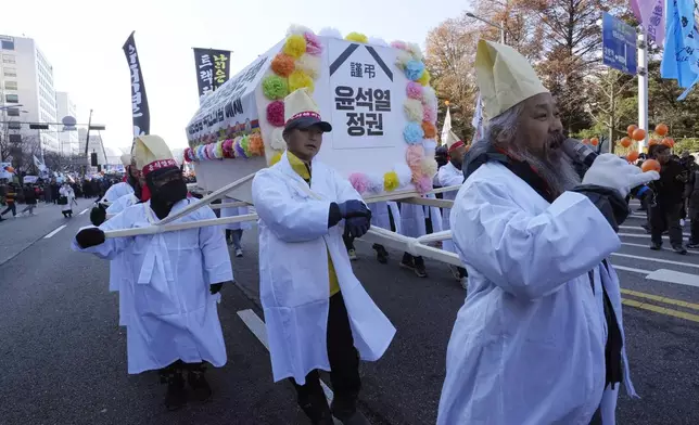 Farmers carry a coffin symbolizing South Korean President Yoon Suk Yeol's government before a rally to demand his impeachment outside the National Assembly in Seoul, South Korea, Saturday, Dec. 14, 2024. The signs read " Yoon Suk Yeol's government. " (AP Photo/Ahn Young-joon)