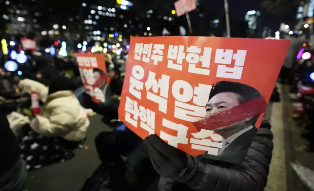 Participants hold banners during a rally to demand South Korean President Yoon Suk Yeol's impeachment outside the National Assembly in Seoul, South Korea, Friday, Dec. 13, 2024. The signs read "Arrest and impeach the rebellion leader Yoon Suk Yeol." (AP Photo/Ahn Young-joon)