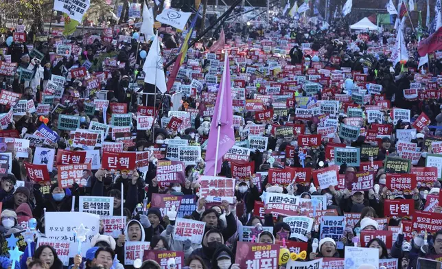 People hold signs before a rally to demand South Korean President Yoon Suk Yeol's impeachment outside the National Assembly in Seoul, South Korea, Saturday, Dec. 14, 2024. The letters read "Impeachment." (AP Photo/Lee Jin-man)