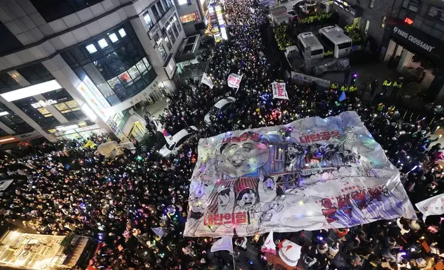 Participants hold a banner depicting South Korean President Yoon Suk Yeol's face on a cartoon train during a rally to demand his impeachment in front of the headquarters of the ruling People Power Party in Seoul, South Korea, Friday, Dec. 13, 2024. (AP Photo/Ahn Young-joon)