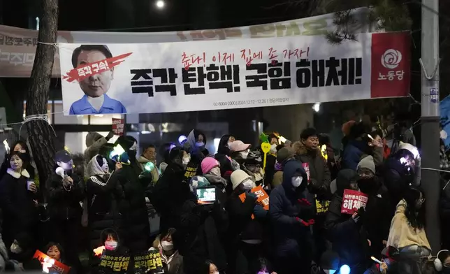 Participants attend a rally to demand South Korean President Yoon Suk Yeol's impeachment outside the National Assembly in Seoul, South Korea, Friday, Dec. 13, 2024. The signs read "Immediately impeachment, disband the ruling People Power Party." (AP Photo/Ahn Young-joon)