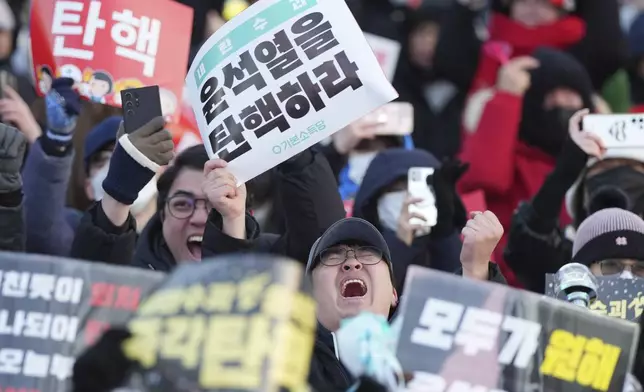Participants react after hearing the news that South Korea's parliament voted to impeach President Yoon Suk Yeol outside the National Assembly in Seoul, South Korea, Saturday, Dec. 14, 2024. The letters read "Impeachment Yoon Suk Yeol." (AP Photo/Lee Jin-man)