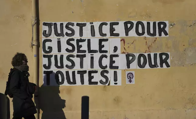 A woman walks past a poster "Justice for Gisele, Justice for all women", Saturday, Dec. 14, 2024 in Avignon, southern France, near the courthouse where the Mazan rape trial is taking place. (AP Photo/Aurelien Morissard)