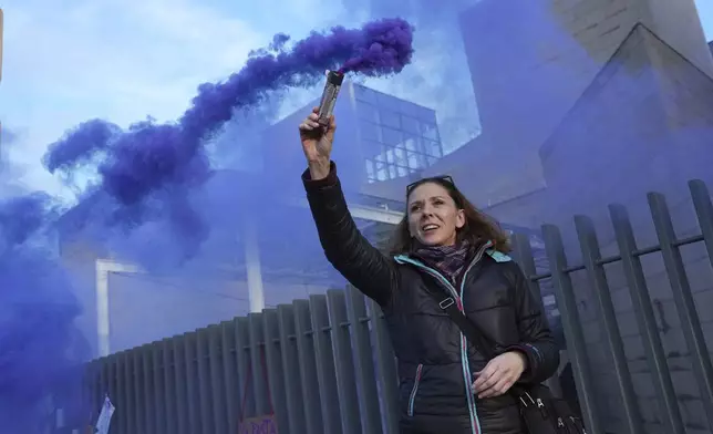 A woman fires a flare outside the Palace of Justice during a women's rights demonstration, Saturday, Dec. 14, 2024 in Avignon, southern France, where the trial of dozens of men accused of raping Gisèle Pelicot while she was drugged and rendered unconscious by her husband is taking place. (AP Photo/Aurelien Morissard)