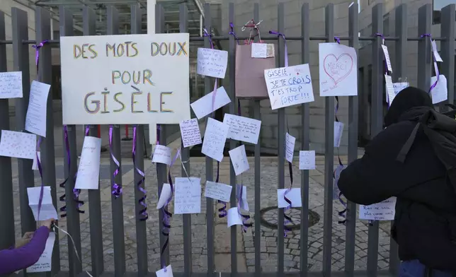 Activists attach nice words for Gisèle Pelicot, one reading "Gentle words for Gisele" on the fence of the Palace of Justice before a women's rights demonstration, Saturday, Dec. 14, 2024 in Avignon, southern France, where the trial of dozens of men accused of raping Gisèle Pelicot while she was drugged and rendered unconscious by her husband is taking place. (AP Photo/Aurelien Morissard)