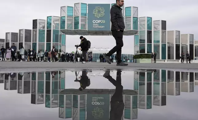 FILE - People arrive for the day at the COP29 U.N. Climate Summit, Nov. 19, 2024, in Baku, Azerbaijan. (AP Photo/Joshua A. Bickel, File)