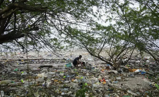 FILE - A man collects items along a polluted coastal area in Metro Manila, Philippines, Sept. 16, 2022. (AP Photo/Aaron Favila, File)