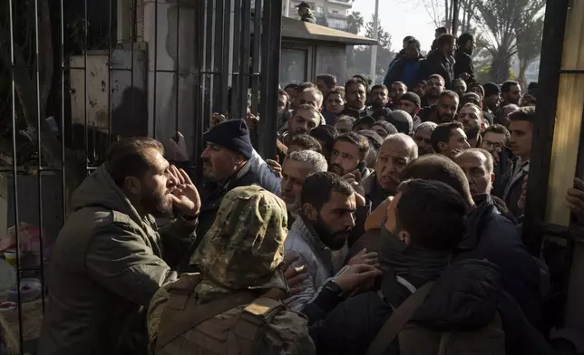 Members of Bashar Assad's army, or a pro-government militia, gather to be registered with Syrian rebels as part of an "identification and reconciliation process" in Damascus, Syria, Saturday, Dec. 21, 2024. (AP Photo/Leo Correa)