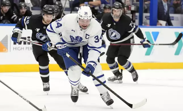 Toronto Maple Leafs center Auston Matthews (34) gets ahead of Tampa Bay Lightning left wing Brandon Hagel (38) and center Anthony Cirelli (71) during the first period of an NHL hockey game Saturday, Nov. 30, 2024, in Tampa, Fla. (AP Photo/Chris O'Meara)