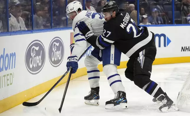 Tampa Bay Lightning defenseman Ryan McDonagh (27) shoves Toronto Maple Leafs center Auston Matthews (34) off the puck during the third period of an NHL hockey game Saturday, Nov. 30, 2024, in Tampa, Fla. (AP Photo/Chris O'Meara)
