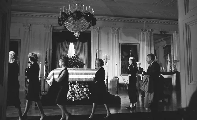 FILE - Members of the White House staff file past the body of John F. Kennedy, lying in repose in a closed, flag-draped coffin in the historic East Room of the Executive Mansion in Washington, Nov. 23, 1963. (AP Photo/Henry Burroughs, File)