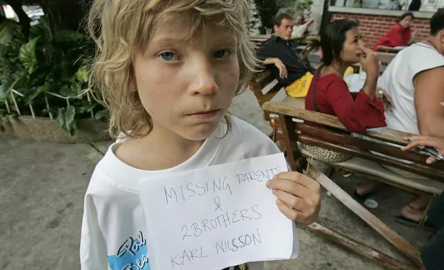 Karl Nilsson of Lulo, Sweden, poses with a sign saying his parents and brothers are missing, in this Dec. 28, 2004, in Phuket, Thailand. The young boys parents were swept out to sea Sunday, Dec. 26, 2004, when the tsunami struck their beach hotel just north of Phuket, Thailand. (AP Photo/David Longstreath/FILE)