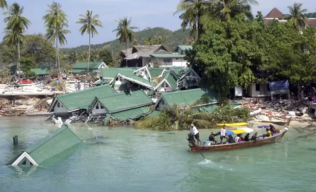 A boat passes by a damaged hotel, at Ton Sai Bay on Phi Phi Island, in Thailand, Dec. 28, 2004. (AP Photo/Suzanne Plunkett, File)