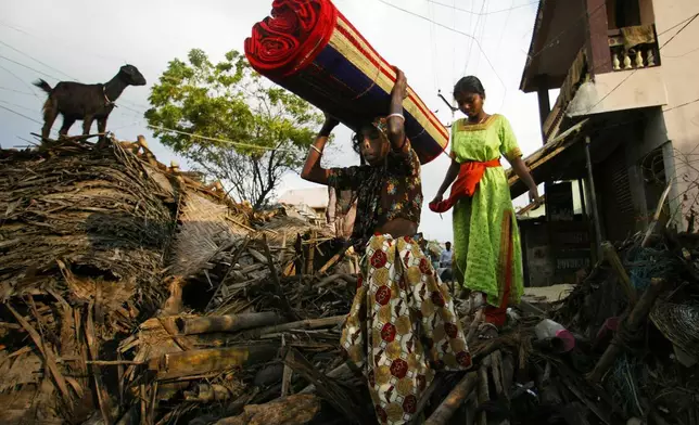 A family makes its way back home accross strewn debris at Nagappattinam, in the Southern Indian state of Tamil Nadu, Friday Dec. 31, 2004. (AP Photo/Saurabh Das, File)