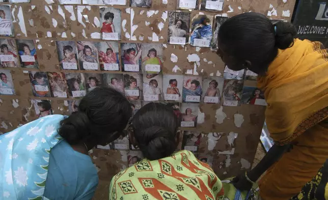 People who lost family members to the deadly tsunami, try to identify them from photos taken before their mass burial and later posted on boards to help families identify their dead, at Vailankanni, near Nagapattinam, India, Saturday Jan. 8, 2005. (AP Photo/Gautam Singh, File)