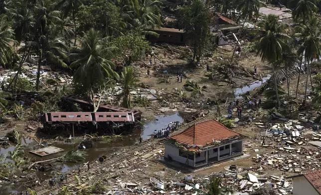 An aerial shot taken from a helicopter shows villagers search for the missing along railroad tracks of a packed train that was swept off the tracks by waves at Telwatte, about 100 kilometers (63 miles) south of Colombo, Sri Lanka, Dec. 29, 2004. (AP Photo/Vincent Thian, File)