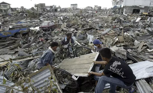 Survivors retrieve a cart from the rubble of the devastated commercial district of Banda Aceh, the capital of Aceh, Friday, Dec. 31, 2004. (AP Photo/Bullit Marquez, File)