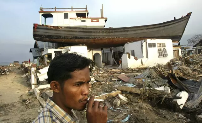 HOLD- An Acehnese man smokes a cigarette near a house on which a fishing boat landed after it was swept away by tsunami in Banda Aceh, Aceh province, Indonesia, Thursday, Feb. 17, 2005. (AP Photo/Dita Alangkara, File)