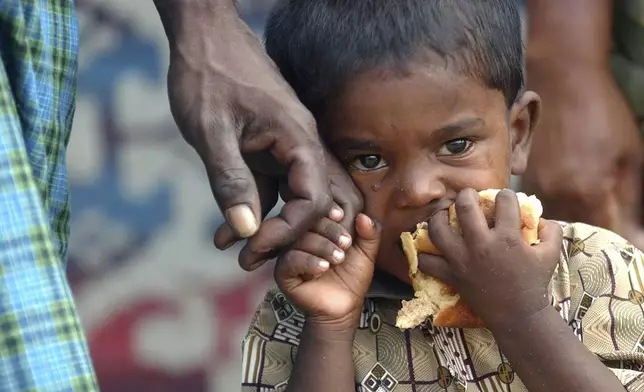 A young Tamil boy stops crying after receiving lunch from local aid workers at a makeshift refugee camp, Tuesday, Jan. 4, 2005, in the village of Palai, just outside of Kilinochchi in north eastern Sri Lanka. (AP Photo/Wally Santana, File)