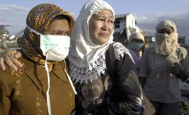 Hernani, center, weeps holding a relative after the bodies of her daughters, victims of the 2004 tsunami, were found in Lampulo, Aceh, Indonesia, Tuesday, Feb. 1, 2005. (AP Photo/Firdia Lisnawati, File)