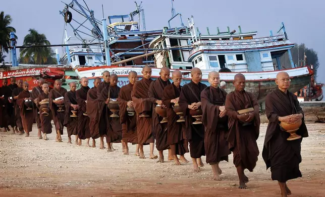 Buddhist Monks from the Asoke community of Bangkok, walk past damaged fishing boats in the tsunami destroyed village of Ban Nam Khem, Thailand, Wednesday, Jan. 19, 2005. (AP Photo/David Longstreath, File)