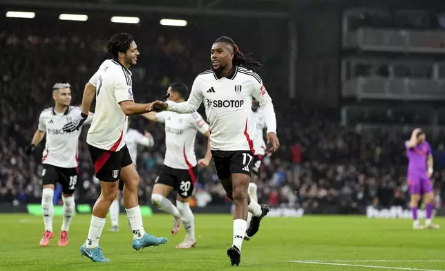 Fulham's Alex Iwobi, right, celebrates after scoring the opening goal during the English Premier League match between Fulham and Wolverhampton Wanderers at Craven Cottage stadium in London, Saturday, Nov. 23, 2024. (Zac Goodwin/PA via AP)