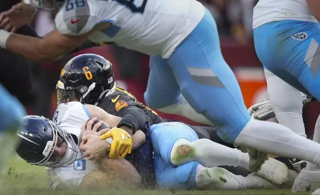 Tennessee Titans quarterback Will Levis, left, recovers a fumbled snap as he is tackled by Washington Commanders linebacker Dante Fowler Jr. (6) during the second half of an NFL football game Sunday, Dec. 1, 2024, in Landover, Md. (AP Photo/Matt Slocum)