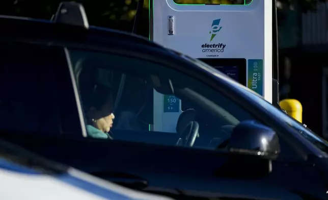 FILE - A driver waits in their car while charging an electric vehicle at an Electrify America station, Oct. 9, 2024, in Seattle. (AP Photo/Lindsey Wasson, File)