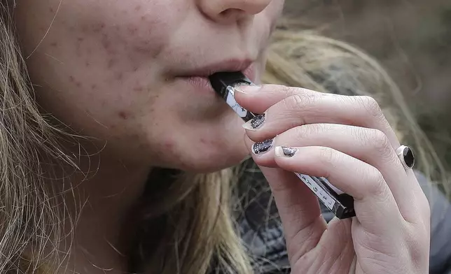 FILE - A high school student uses a vaping device near a school campus in Cambridge, Mass., April 11, 2018. (AP Photo/Steven Senne, File)