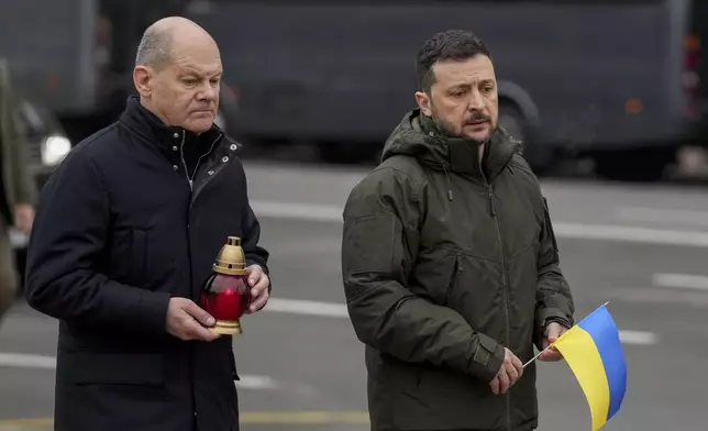 Ukraine's President Volodymyr Zelenskyy, right, and German Chancellor Olaf Scholz attend a ceremony of honoring fallen soldiers near the People's Memorial of National Memory in Kyiv, Ukraine, Monday, Dec.2, 2024. (AP Photo/Evgeniy Maloletka)