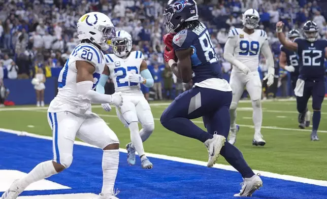 Tennessee Titans tight end Chig Okonkwo, right, scores a two point conversion against the Indianapolis Colts safety Nick Cross (20) during the second half of an NFL football game Sunday, Dec. 22, 2024, in Indianapolis. (AP Photo/Michael Conroy)