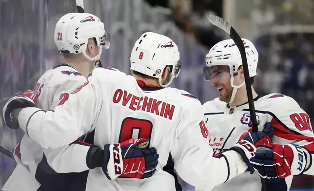 Washington Capitals' Alex Ovechkin (8) celebrates after his empty-net goal against the Toronto Maple Leafs with Aliaksei Protas (21) and Pierre-Luc Dubois (80) during third-period NHL hockey game action in Toronto, Saturday, Dec. 28, 2024. (Frank Gunn/The Canadian Press via AP)