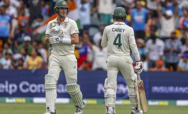 Australia's captain Pat Cummins, left talks to Alex Carey during play on day five of the third cricket test between India and Australia at the Gabba in Brisbane, Australia, Wednesday, Dec. 18, 2024. (AP Photo/Pat Hoelscher)