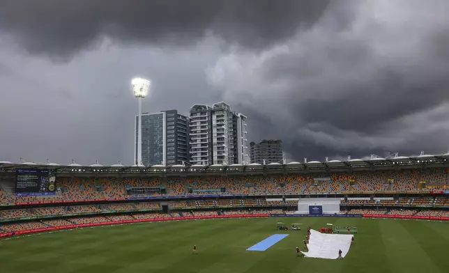 Ground staff place covers over the pitch as rain suspends play on day five of the third cricket test between India and Australia at the Gabba in Brisbane, Australia, Wednesday, Dec. 18, 2024. (AP Photo/Pat Hoelscher)