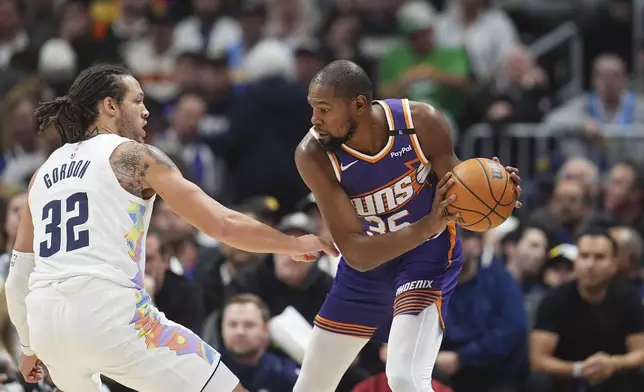 Phoenix Suns forward Kevin Durant, right, looks to pass the ball as Denver Nuggets forward Aaron Gordon defends in the first half of an NBA basketball game, Monday, Dec. 23, 2024, in Denver. (AP Photo/David Zalubowski)