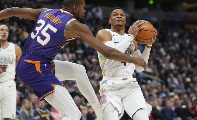 Denver Nuggets guard Russell Westbrook, right, drives to the basket as Phoenix Suns forward Kevin Durant (35) defends in the first half of an NBA basketball game Monday, Dec. 23, 2024, in Denver. (AP Photo/David Zalubowski)