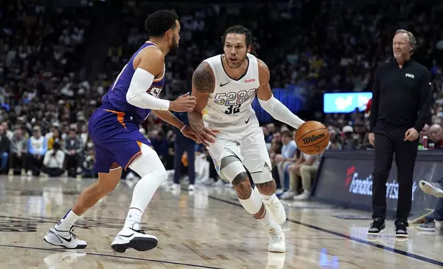 Denver Nuggets forward Aaron Gordon, right, drives past Phoenix Suns guard Tyus Jones in the first half of an NBA basketball game Monday, Dec. 23, 2024, in Denver. (AP Photo/David Zalubowski)