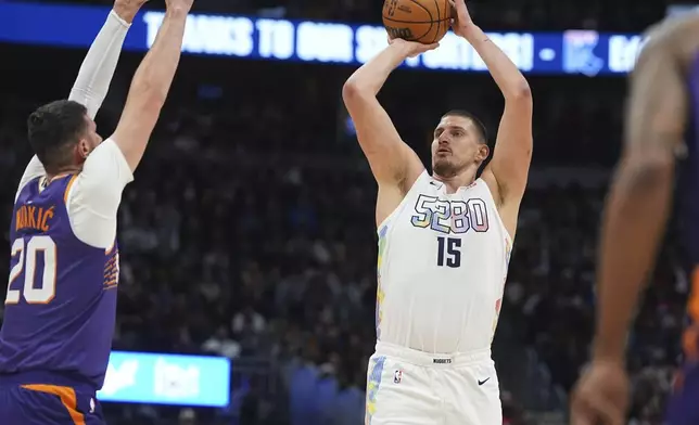 Denver Nuggets center Nikola Jokic, right, goes up for a basket as Phoenix Suns center Jusuf Nurkic defends in the first half of an NBA basketball game Monday, Dec. 23, 2024, in Denver. (AP Photo/David Zalubowski)