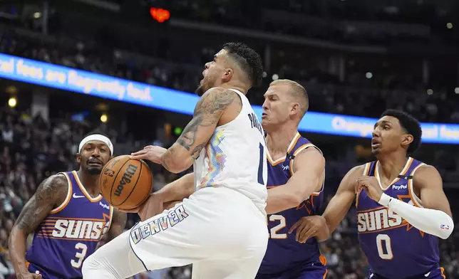 Denver Nuggets forward Michael Porter Jr., center left, drives to the basket as, from back left to right, Phoenix Suns guard Bradley Beal, center Mason Plumlee and forward Ryan Dunn defend in the first half of an NBA basketball game Monday, Dec. 23, 2024, in Denver. (AP Photo/David Zalubowski)