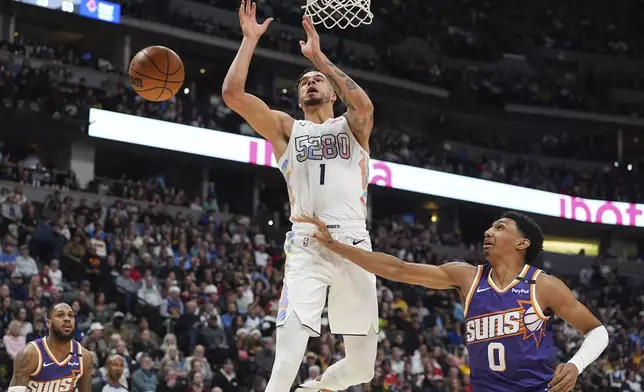 Denver Nuggets forward Michael Porter Jr. (1) loses control of a pass while driving to the basket as Phoenix Suns forward Ryan Dunn (0) defends in the first half of an NBA basketball game Monday, Dec. 23, 2024, in Denver. (AP Photo/David Zalubowski)