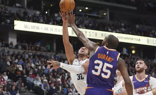 Phoenix Suns forward Kevin Durant, front, blocks a shot by Denver Nuggets forward Aaron Gordon in the first half of an NBA basketball game Monday, Dec. 23, 2024, in Denver. (AP Photo/David Zalubowski)