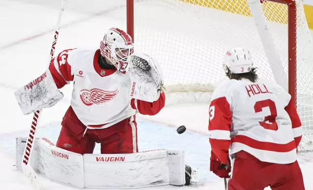 Detroit Red Wings goaltender Alex Lyon is scored on by Montreal Canadiens' Brendan Gallagher, not shown, as Red Wings' Justin Holl looks on during the second period of an NHL hockey game in Montreal, Saturday, Dec. 21, 2024. (Graham Hughes/The Canadian Press via AP)