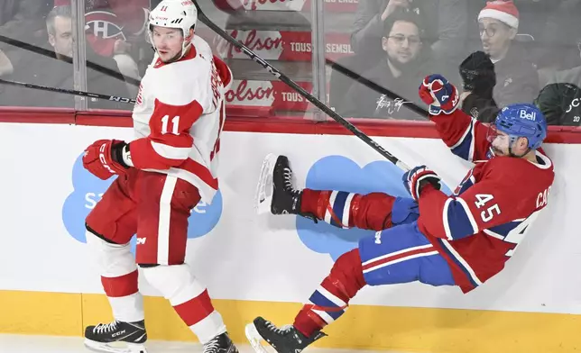 Montreal Canadiens' Alexandre Carrier (45) is upended by Detroit Red Wings' Vladimir Tarasenko (11) during the third period of an NHL hockey game in Montreal, Saturday, Dec. 21, 2024. (Graham Hughes/The Canadian Press via AP)