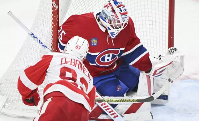 Montreal Canadiens goaltender Sam Montembeault, top, makes a glove-save against Detroit Red Wings' Alex DeBrincat (33) during second-period NHL hockey game action in Montreal, Saturday, Dec. 21, 2024. (Graham Hughes/The Canadian Press via AP)