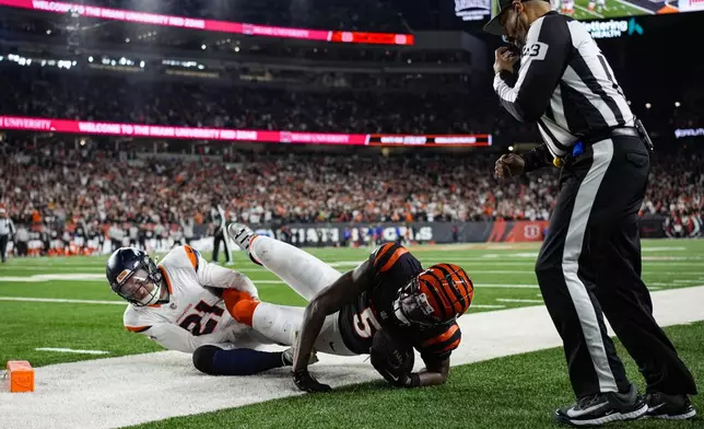 Cincinnati Bengals wide receiver Tee Higgins (5) is tackled by Denver Broncos cornerback Riley Moss (21) after a touchdown during overtime of an NFL football game in Cincinnati, Saturday, Dec. 28, 2024. (AP Photo/Carolyn Kaster)