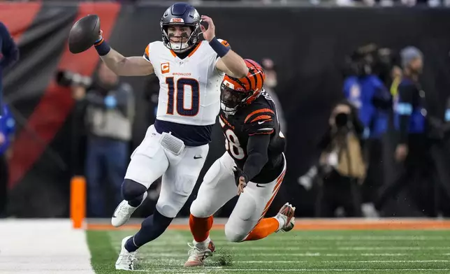 Denver Broncos quarterback Bo Nix (10) is chased out of bounds by Cincinnati Bengals defensive end Joseph Ossai (58) during the first half of an NFL football game in Cincinnati, Saturday, Dec. 28, 2024. (AP Photo/Carolyn Kaster)