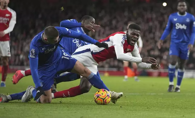 Arsenal's Thomas Partey, centre, challenges for the ball with Everton's Vitaliy Mykolenko during the English Premier League soccer match between Arsenal and Everton at Emirates Stadium in London, Saturday, Dec. 14, 2024. (AP Photo/Kin Cheung)