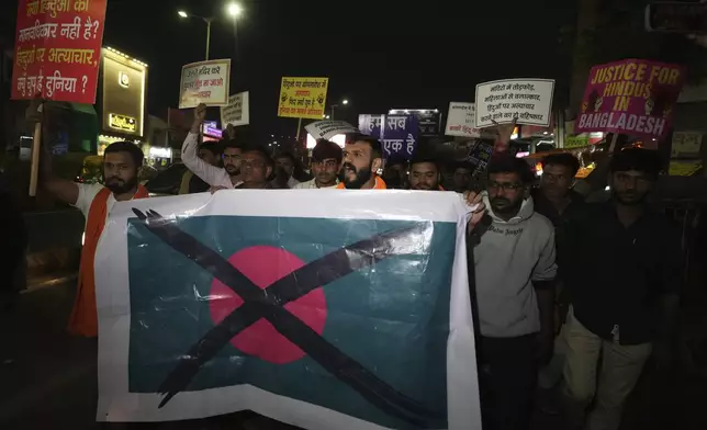 Activists of Bajarang dal, a Hindu rights group, carry a defaced symbolic flag of Bangladesh, during a protest against the alleged attacks on Hindus in Bangladesh, in Ahmedabad, India, Wednesday, Dec. 11, 2024. (AP Photo/Ajit Solanki)